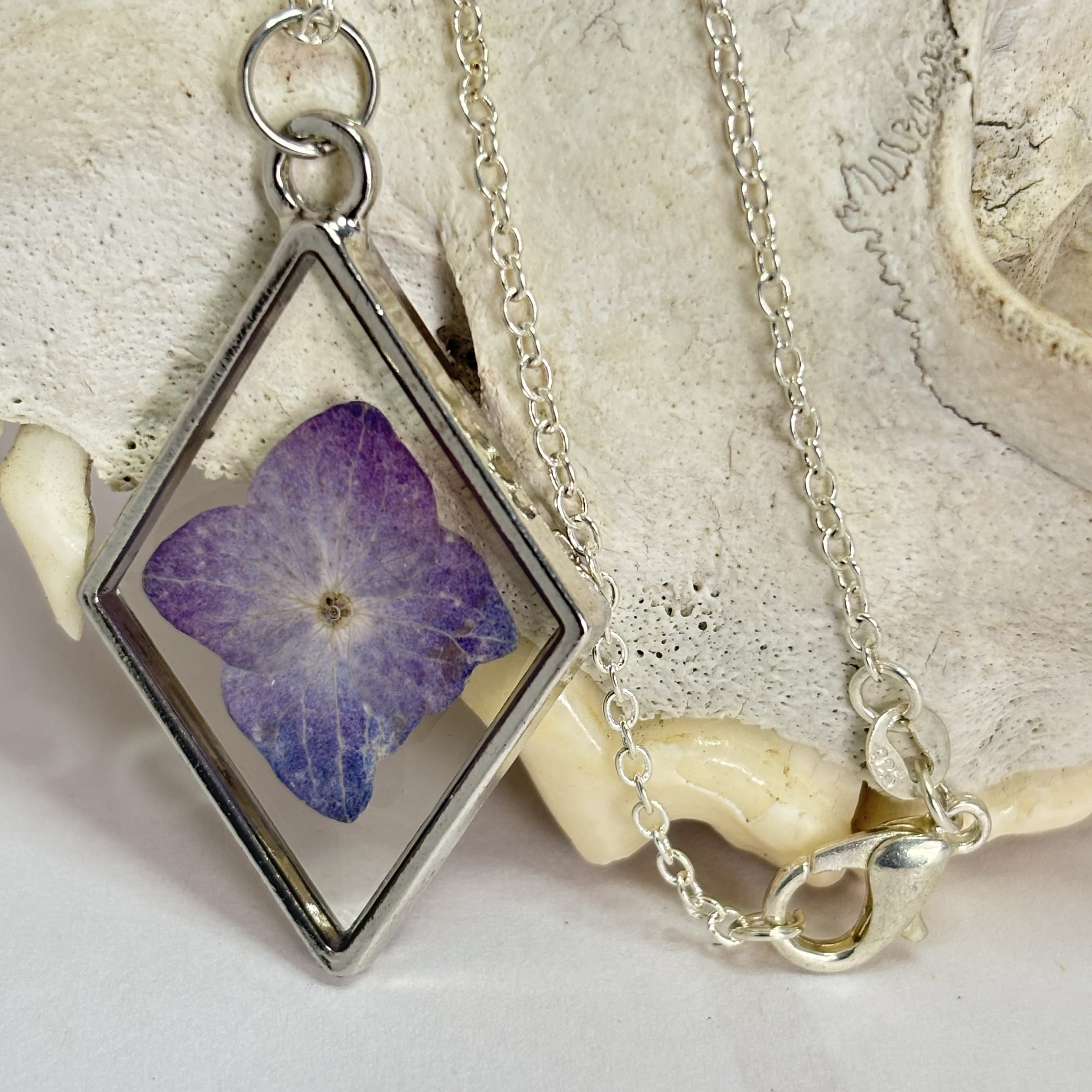 Necklace with a pendant featuring a pressed purple flower 