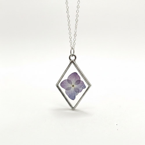 Diamond-shaped pendant with a pressed purple flower